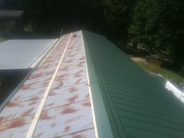 Old rusted panels beside newly installed green metal roofing — Wind Damage Roof Repair by Roofing Brothers in Lorraine