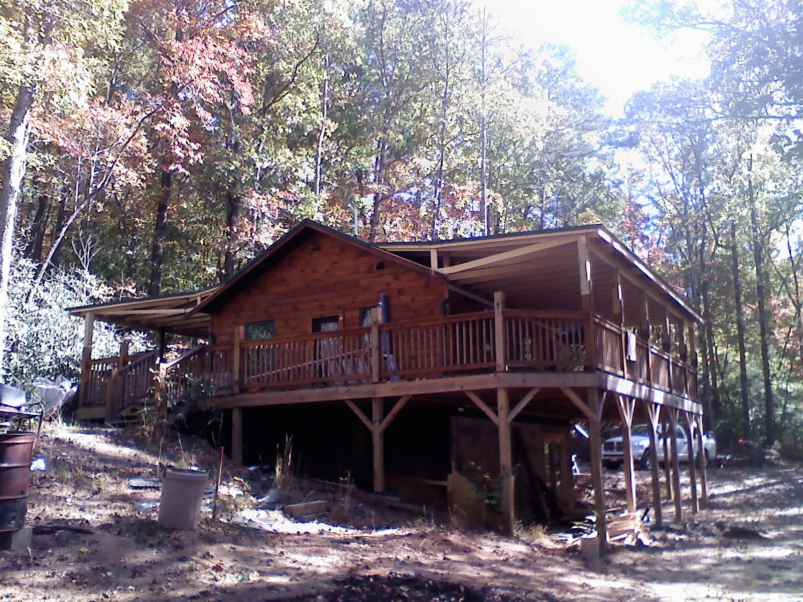 Log cabin with a wraparound porch and metal roof in the fall in Lorraine