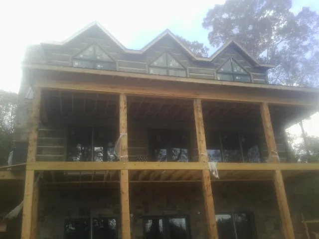 Dormers and porch framing on a large log home under construction — Roof Coating work by our crew in Lorraine