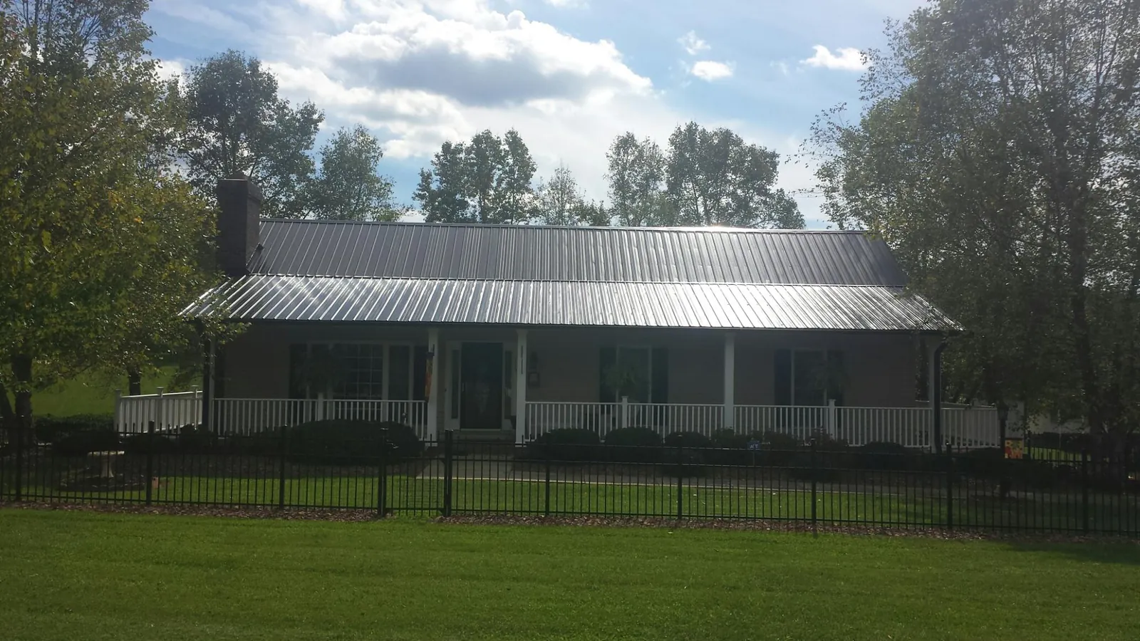 Gray metal roof on a brick ranch with a full width front porch — Gutter Guard Installation work by our crew in Lorraine