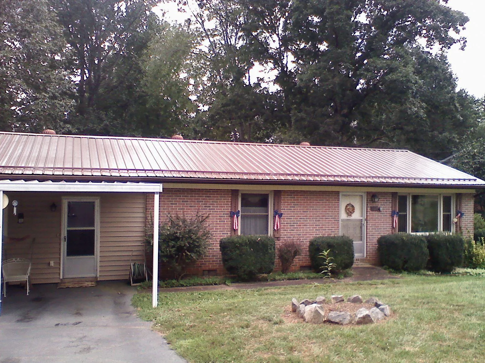 Bronze metal roof and carport on a brick ranch home — Roof Repair work by our crew in Lorraine