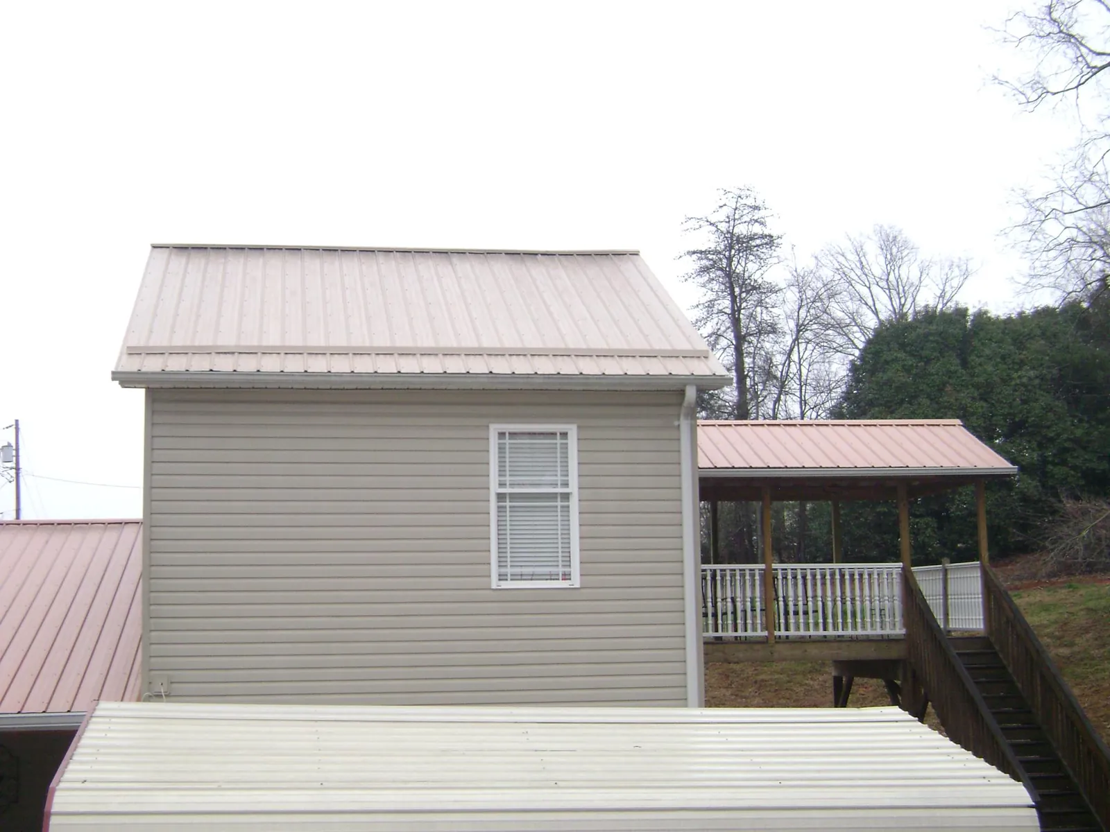 Tan metal roofs on a two story addition and attached porch, from a Roof Replacement job in Lorraine