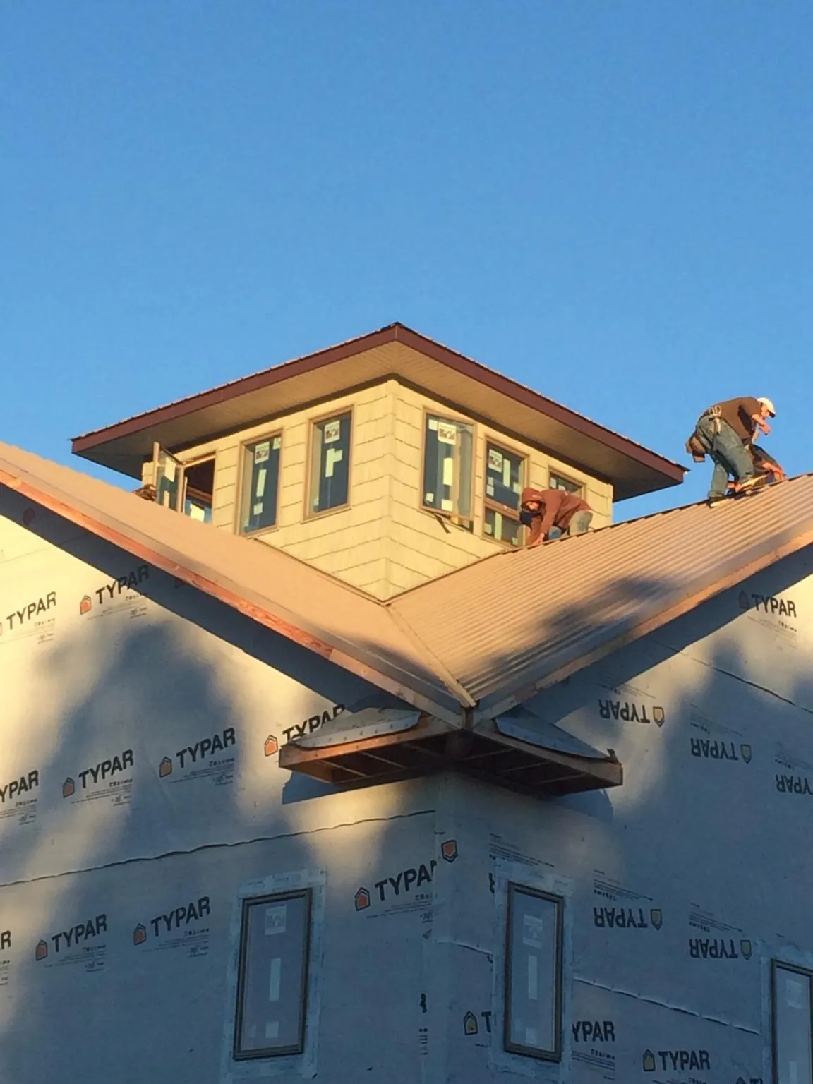 Roofers working around a rooftop cupola on a new metal roof at sunset — Roof Waterproofing in Lorraine by Roofing Brothers